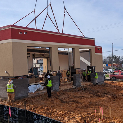 A construction crew is utilizing modular construction techniques for the off site construction of a fast food restaurant.