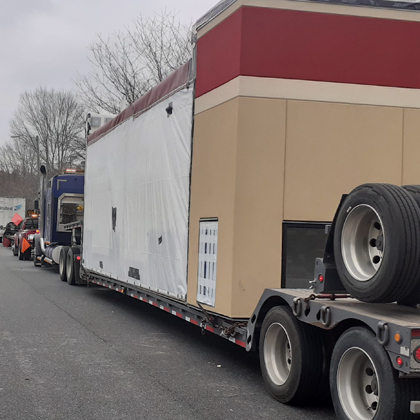 A semi truck with a modular construction trailer attached to it.