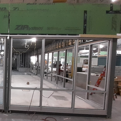 A large glass door is being installed in a building using modular construction techniques.